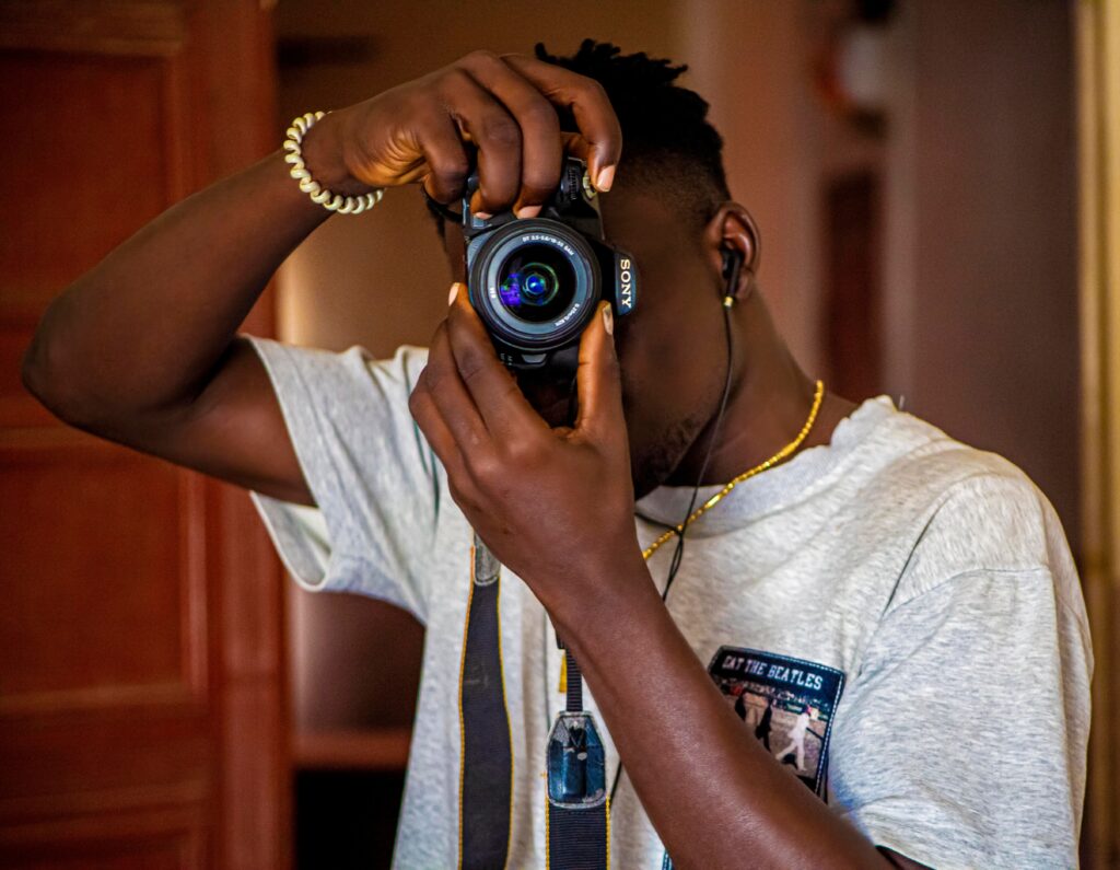 African man photographing indoors with a DSLR. Creativity and focus in modern photography.